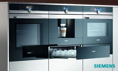 Offene Küche mit gedecktem Tisch, sechs Personen beim Abendessen, moderne Geräte im Hintergrund. Offene Küche mit gedecktem Tisch, sechs Personen beim Abendessen, moderne Geräte im Hintergrund.